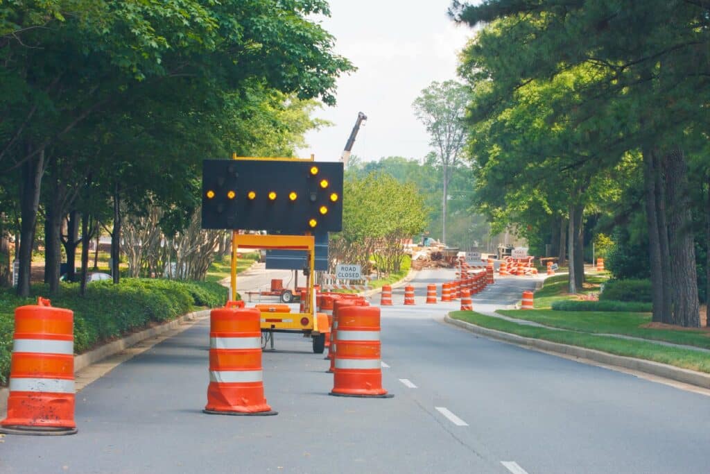 trees near a road that has construction cones