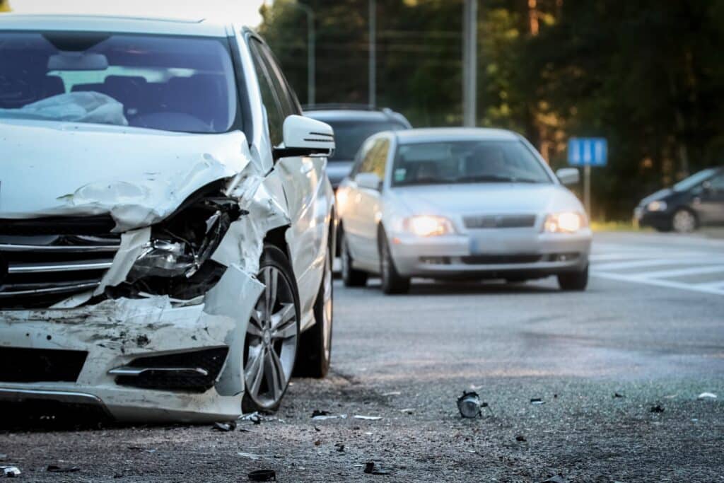 Front of white car involved in an accident with cars in the background