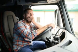 Male truck diver feeling tired and yawning during the ride